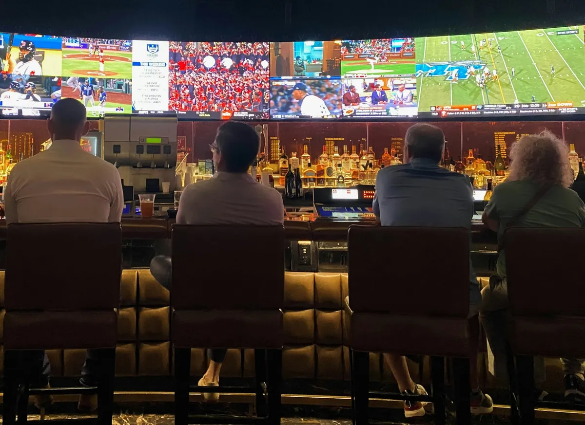 Spectators watching multiple sports screens at a bar, from the source website